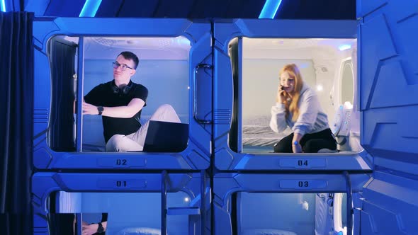 Young People are Opening and Closing Doors of a Capsule Hotel