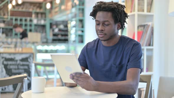 African Man Using Digital Tablet in Cafe