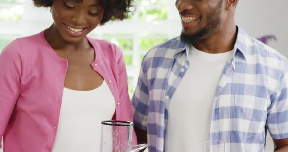 Happy man and woman preparing juice in juicer