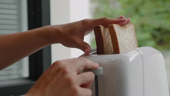 Female Hands Putting Bread Into Toaster