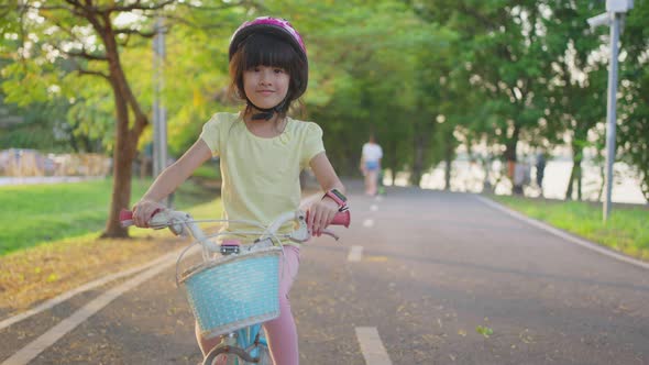 Asian young kid riding small bicycle on road playing sport activity outdoor in the park with smile.