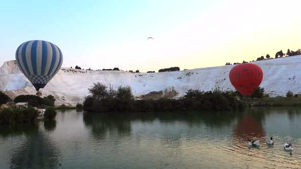 Hot Air Balloons in White Travertines and Lake of Pamukkale, a Touristic Natural World Heritage Site