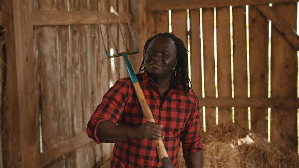 African Farmer Holding Fork Over His Shoulder in the Barn