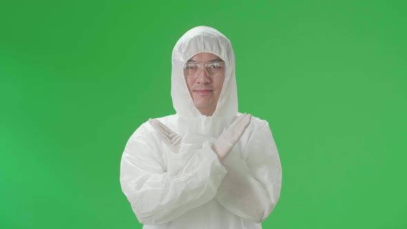 Asian Man Wear Protective Uniform Ppe And Showing Stop Sign In The Green Screen Studio