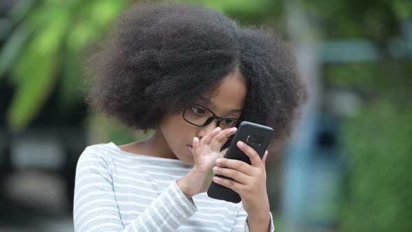 Young Cute African Girl with Afro Hair Using Phone in the Streets Outdoors