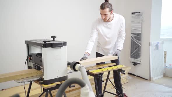 Carpenter in Protective Gloves for Working with Wood on the Planing Machine