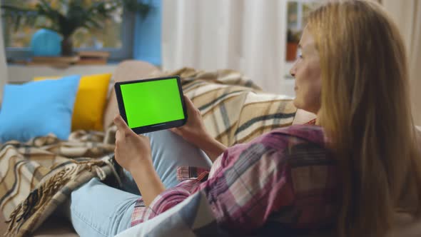 Back View of Happy Mature Woman with Tablet Pc Computer Having Video Call Relaxing on Couch at Home