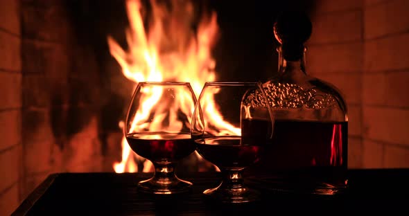 Two Glasses of Cognac and a Bottle Near the Fireplace