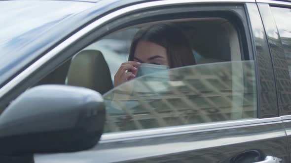 Young Brunette Woman Putting on Protective Mask, Closing Side Window