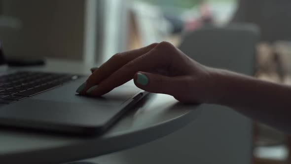 Closeup Tracking Shot of Unrecognizable Young Woman Touching Touchpad of Laptop Sitting at Table in