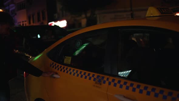 a Man and a Girl Get Into a Taxi in the Evening City