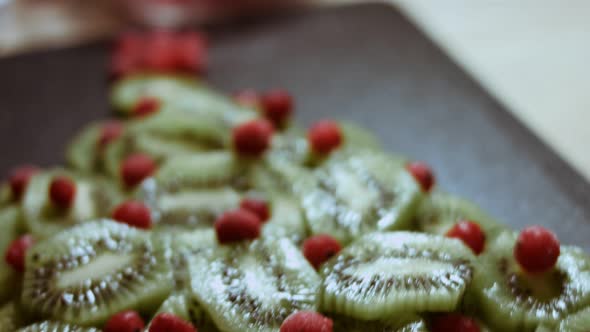 Juicy Fresh Kiwi Slices and Frozen Red Currant Arranged in a Shape of Christmas Tree on a Black