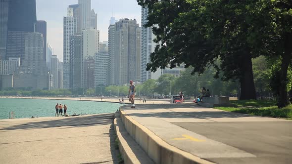 A young woman goes longboard skateboarding with the Chicago, Illinois skyline in the background.