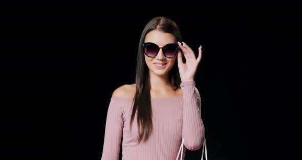 Smiling Stylish Woman in Sunglasses and Pink Dress Carrying on Pink Bag Happy Lady with Dark Hair