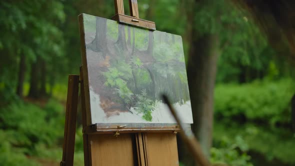 Unrecognizable Woman Paintress Looks at a Picture Painted By Her in a Forest
