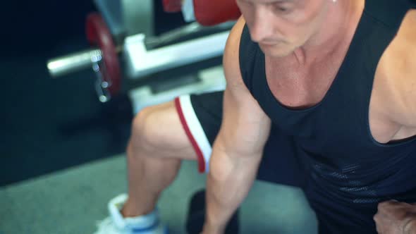 Muscular Bodybuilder Guy Doing Exercises with Dumbbells in the Gym