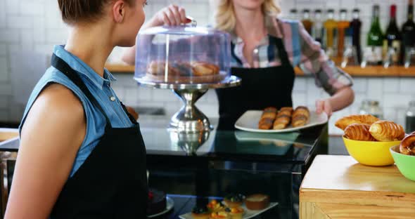 Waitress standing at counter while colleague working in the background