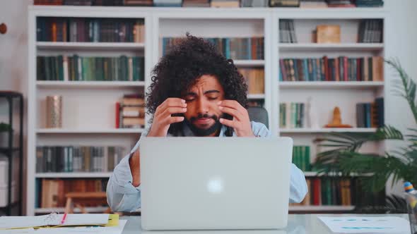 Young Upset Arabian Man Looks at Laptop Screen Grabs Head Sits at Desk in Office