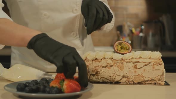 Confectioner Young Woman Decorates Meringue Roll Dessert with Fruits and Berries