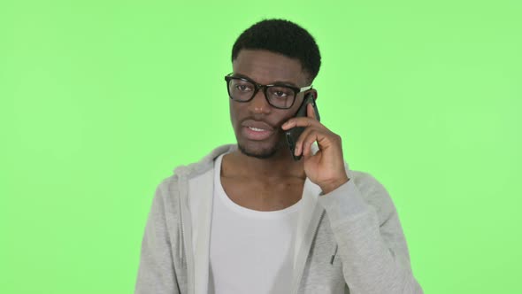 African Man Talking on Phone on Green Background