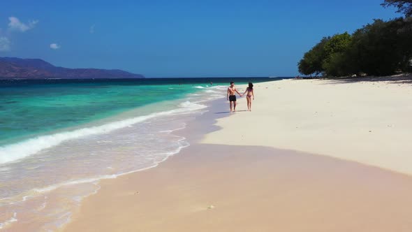 Boy and girl tan on paradise shore beach holiday by blue green sea with bright sand background of Gi