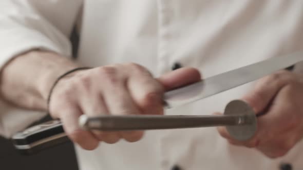 Cook Sharpens Knife on Knife on Domestic Kitchen
