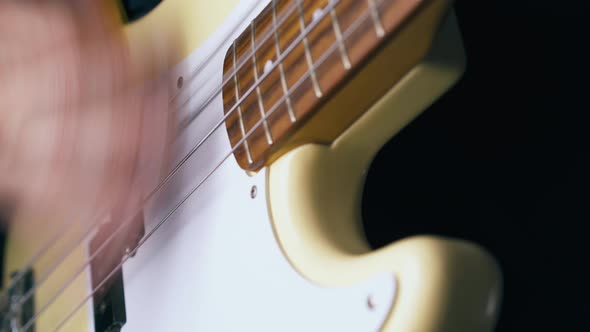 Bassist Plays White Guitar Holding Yellow Pick Closeup