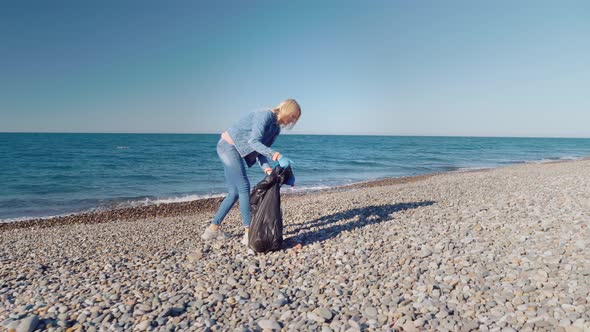 a woman collecting cleaning plastic bottles on the beach,