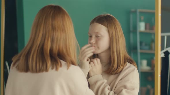 A Red Haired Teenage Girl Examines Her Reflection in the Mirror