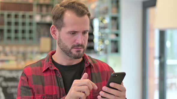 Portrait of Young Man Reacting to Loss on Smartphone