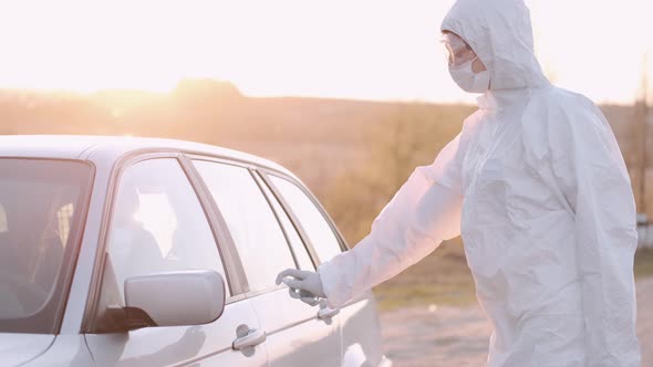 Woman in Full-covering Equipment Is Spraing Antibacterial Liquid on Car's Door Handle