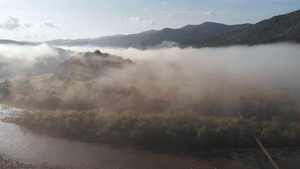 Aerial Drone Flight View Over Low Clouds and Morning Mist Covered Mountain Slopes at Sunrise