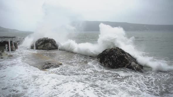 ocean waves crash violently against rocks on the coast in a severe storm. Slow motion, static