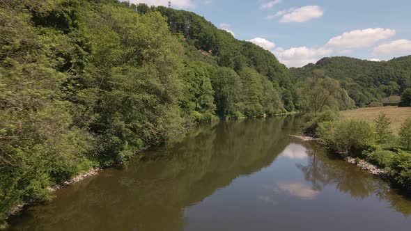 The calm brown waters of the Sieg river under a blue sky with few soft clouds. Aerial wide angle tra