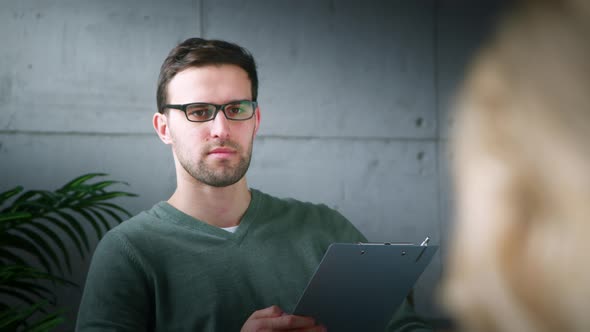 A young psychologist with glasses listening to a girl at a consultation in the office