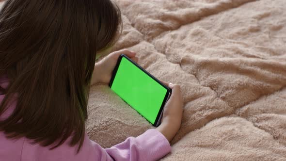 A Girl of 78 Years Old Uses a Mobile Phone with a Green Screen