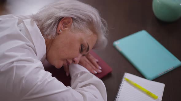 High Angle View Exhausted Mature Businesswoman Sleeping on Table in Office