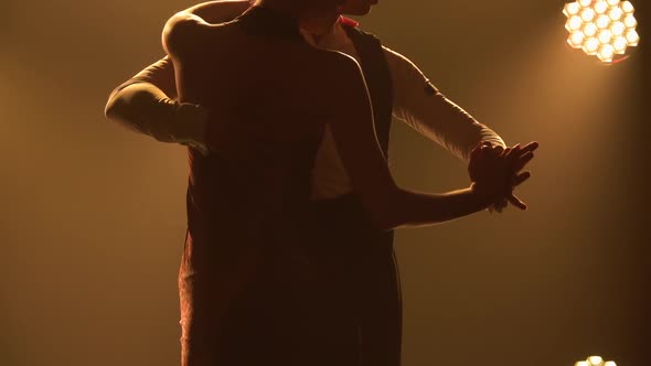 Silhouettes Pair of Dancers Performing Elements of Argentine Dance Appear Against the Smoky Yellow