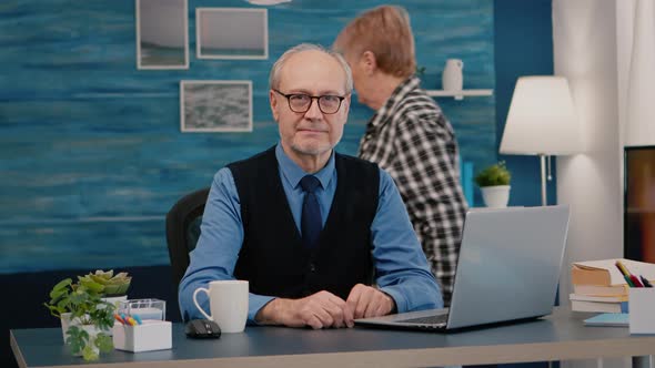 Elderly Businessman Entrepreneur Sitting in Workspace Looking at Camera