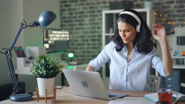 Cute Woman Having Fun in Office Listening To Music Dancing Using Laptop Alone