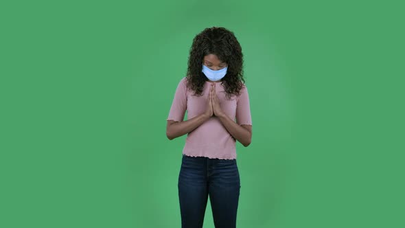 Portrait of Beautiful African American Young Woman in Medical Mask Is Looking Straight and Prays