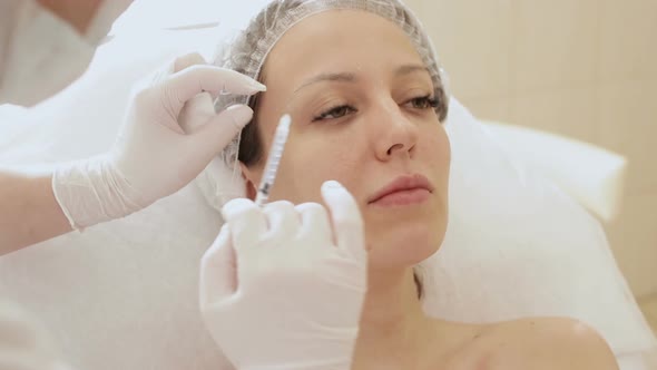 Beautician Hands in Gloves Making Face Aging Injection in a Female Skin