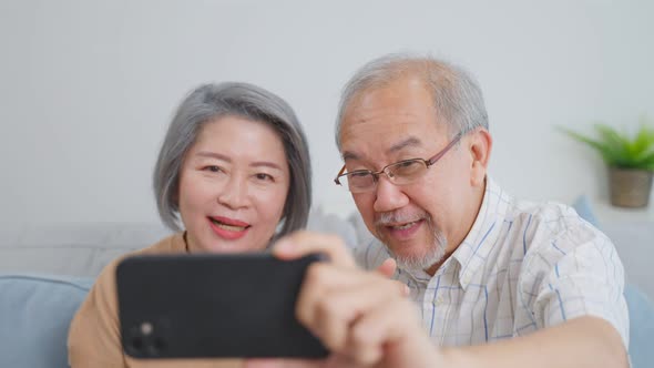 Asian senior old couple video call with family in living room at home.