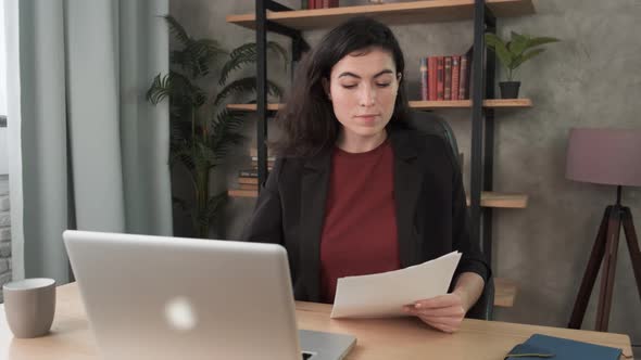 Young Woman Employee in the Office at the Computer. Brunette Girl Enters Text From a Document Into a