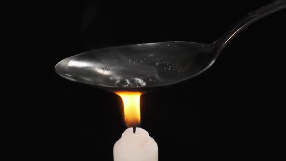 Cooking Heroin on a Spoon Over the Flame of Candle