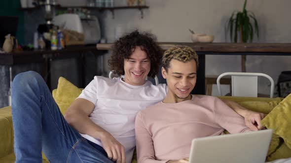 Two Male Gay Couple Using Laptop Computer for Video Calling or Surfing Internet Together