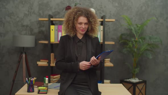 Lovely Businesswoman with Folder Looking with Cheerful Smile Indoors