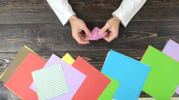Man Folding Origami From Pink Paper.