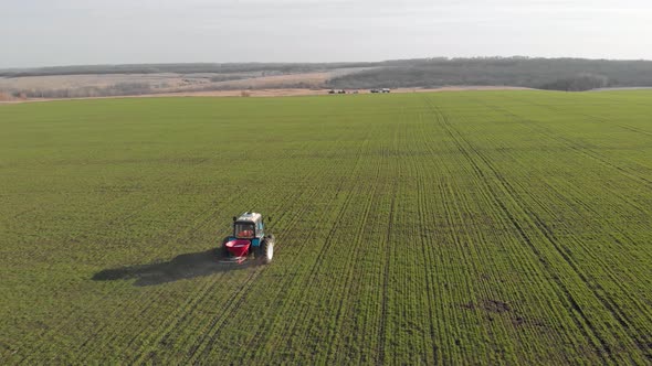 Tractor Spreading Artificial Fertilizers in Green Field. Farmer Fertilizing Arable Land with