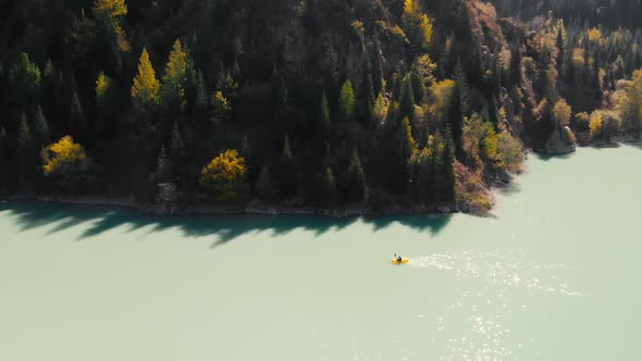 Man is Paddling on Raft Boat in the Mountain Lake